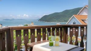 a balcony with a table with two drinks on it at Geoje Gaonara Pension in Geoje