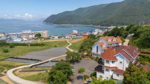 a large house on a hill next to a body of water at Geoje Gaonara Pension in Geoje