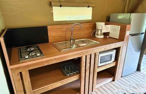 a kitchen with a sink and a stove and a refrigerator at Lodge Mini-Wood in Les Rochettes