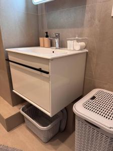 a bathroom with a white sink and a basket at comfortable apartment in Vancouver
