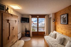 a living room with a couch and a sliding glass door at L'Ecrin des Myrtilles - Appartement cosy - Piscine et vue montagne - Alpes - Val d'Arly - Aravis et Beaufortain in Flumet