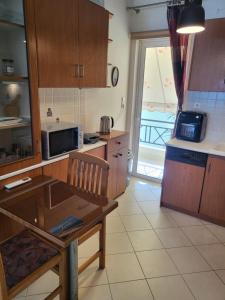 a kitchen with wooden cabinets and a table with a microwave at Διαμέρισμα "LENIA" μπροστά στην θάλασσα! in Kiaton +19 photos