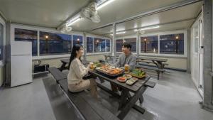 a man and a woman sitting at a table with food at Yeosu Onueli Pension in Yeosu