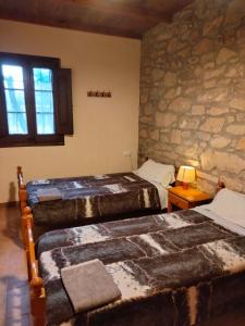 ein Schlafzimmer mit zwei Betten und einer Steinwand in der Unterkunft Moixons in Calonge de Segarra + 4 Fotos