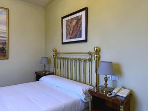 a bedroom with a bed and two tables with lamps at Hotel San Rosendo in Ourense +5 photos