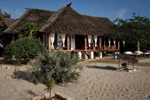a house with a thatched roof on a sandy beach at Mandarina Beach House in Lamu