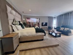 a bedroom with a large bed and a living room at Calypso Sunset Accommodation in Langebaan