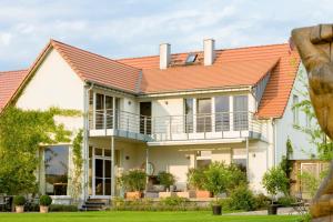 an image of a house with an orange roof at Ferienhaus Peeneblick - exklusives Traumhaus in Direktlage am Wasser mit Bootssteg und Aussensauna in Rankwitz