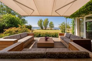 a patio with couches and a table with flowers at Ferienhaus Peeneblick - exklusives Traumhaus in Direktlage am Wasser mit Bootssteg und Aussensauna in Rankwitz