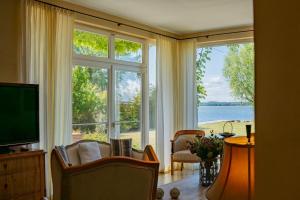 a living room with a television and a large window at Ferienhaus Peeneblick - exklusives Traumhaus in Direktlage am Wasser mit Bootssteg und Aussensauna in Rankwitz