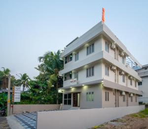 a white building with trees in the background at FORA Inn in Cochin