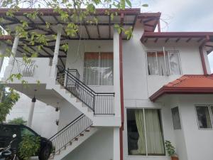 a white house with stairs and a car parked in front at Sun Power Villa in Hokandara South