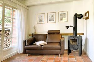 a living room with a leather chair and a stove at Süderende- Hus Lillesol in Süderende