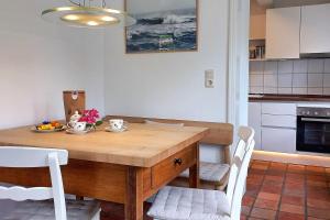 a kitchen with a wooden table and white chairs at Süderende- Hus Lillesol in Süderende +12 photos