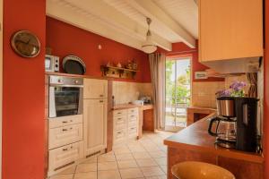 a kitchen with red walls and white cabinets at Ferienhaus Kranich in Krienke +25 photos