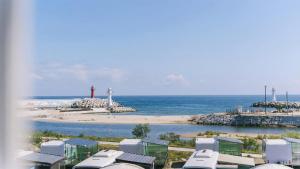 a view of a beach with a lighthouse and the ocean at Gangneung Basecamp Pension in Gangneung