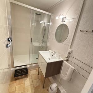 a white bathroom with a shower and a sink at La Balastière in Beaumont-en-Véron