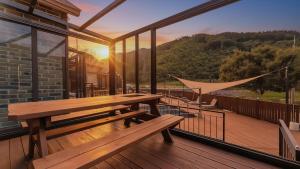 a wooden picnic table on a balcony with the sunset at Gapyeong Haneulsup Spa Pension in Gapyeong