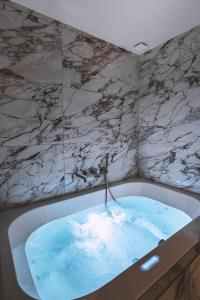 a bathroom with a bath tub with blue water at Suite Cognac - International Palace - Jacuzzi in Vichy +23 photos