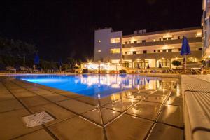 a swimming pool in front of a building at night at Christina Beach Hotel in Kissamos