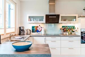 a kitchen with white cabinets and a blue bowl on a counter at Kramerhof Ferienhaus Luv und Lee in Parow +15 photos