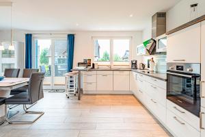 a kitchen with white cabinets and a table and chairs at Kramerhof Ferienhaus Luv und Lee in Parow
