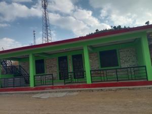 a green building with a tower in the background at Pindari Homestay in Bāgeshwar