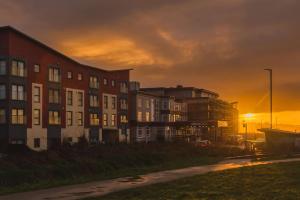 a building with the sunset in the background at Panoramic Sea-View Family Appartment , Free Parking, Sleeps 6 , Walk to Beach, Station, & Town in Newquay
