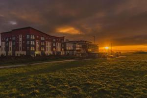 a building on a field with the sunset in the background at Panoramic Sea-View Family Appartment , Free Parking, Sleeps 6 , Walk to Beach, Station, & Town in Newquay