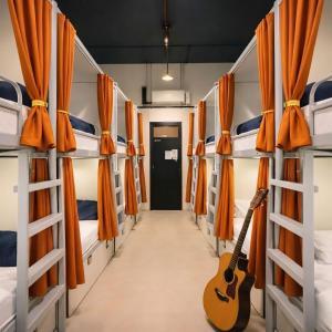 a guitar in the middle of a room with bunk beds at Metro POD Hotel at New Delhi Metro & Railway Station in New Delhi