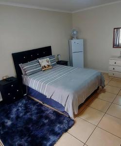 a bedroom with a large bed with a blue rug at Karoo House Guesthouse in Somerset East