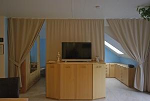 a living room with a flat screen tv and curtains at Beilsteiner Ferienwohnungen in Beilstein