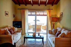 a living room with two couches and a coffee table at Yiannis Seafront Villa Paleokastritsa in Paleokastritsa