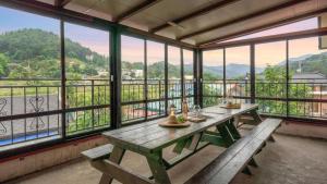 a room with a table and benches and windows at Gapyeong Maplein Pension in Pocheon
