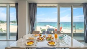 a table with food and a view of the beach at Goseong Moneblue Pension in Goseong
