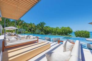 an outdoor patio with white couches and a swimming pool at Villa Brisa in Punta Mita in Punta Mita
