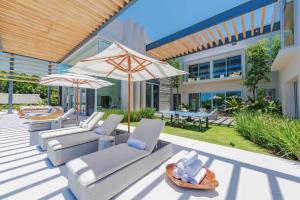 a patio with chairs and umbrellas in front of a building at Villa Brisa in Punta Mita in Punta Mita