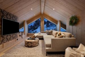 a living room with a couch and a flat screen tv at FJELLRO Private Alpine Lodge Høgevarde in Flå