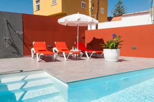 - une piscine avec 2 chaises et un parasol dans l'établissement Sol y Mar El Salobre, à Maspalomas