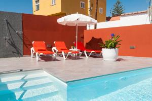 una piscina con 2 sillas y una sombrilla en Sol y Mar El Salobre, en Maspalomas