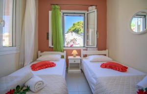 two beds in a room with a window at Dora's Beach Cottages in Planos
