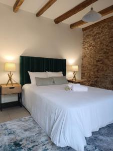 a bedroom with a large white bed and a brick wall at Retiro do Lavrador in Alvaiázere +72 photos