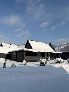 a house with snow on the roof of it at Grey House in Kvasy