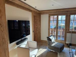 a living room with a tv and chairs and windows at Petite Fraise in Gstaad
