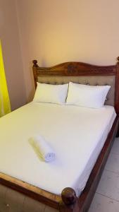 a bed with a wooden headboard with a towel on it at Manja Homes in Ruiru