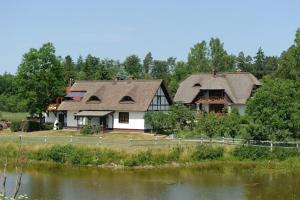 a large house with a thatched roof next to a lake at holiday home with thatched roof, Rekowo in Rekowo