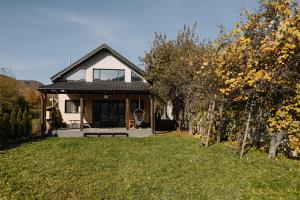 a small white house with a porch on a lawn at Chalet Odette in Pangarati