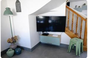 a living room with a flat screen tv on a wall at Maison spacieuse au coeur du Centre - Plage à pied in Luc-sur-Mer +23 photos
