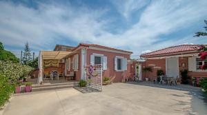 a small pink house with a patio at Dora's Beach Cottages in Planos