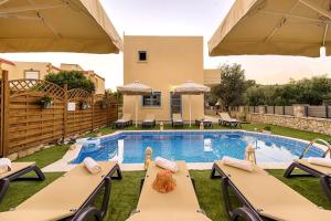 a villa with a swimming pool with tables and chairs at Lindos Luxury Retro Villas in Lindos
